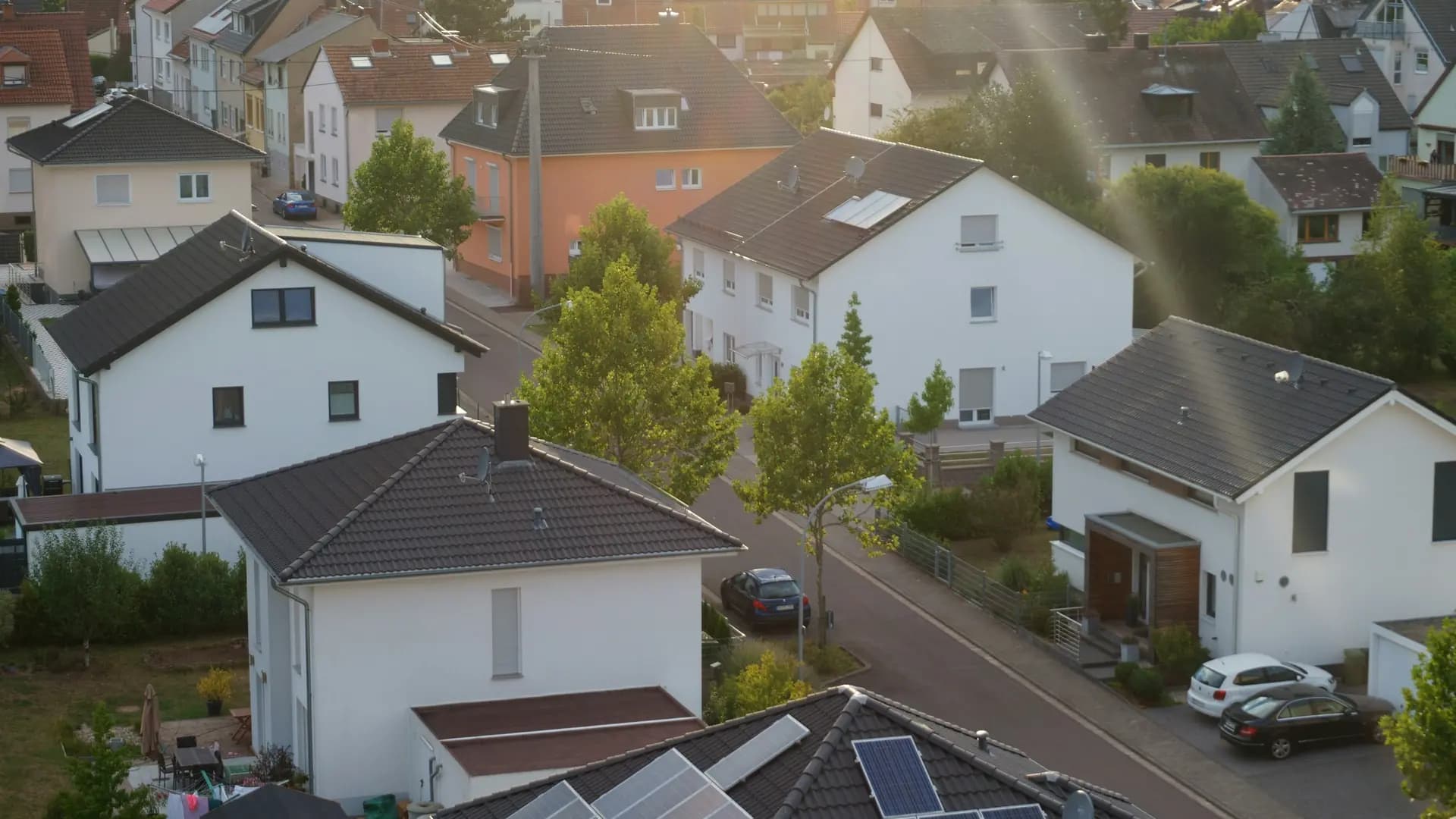 Vue aérienne d'un quartier résidentiel dont les maisons sont équipées de panneaux solaires en toiture, sous une lumière chaude de fin de journée